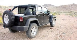 A Jeep Wrangler in black, parked on a dirt road near Wichita, KS