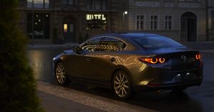 A view of the rear and left side of a silver 2019 Mazda3 sedan parked on the street in Wichita, KS
