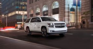 A white 2020 Chevy Suburban driving at night through Sheboygan, WI